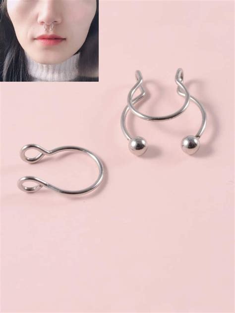 A Pair Of Silver Ear Hooks On Top Of A Pink Background With An Image Of