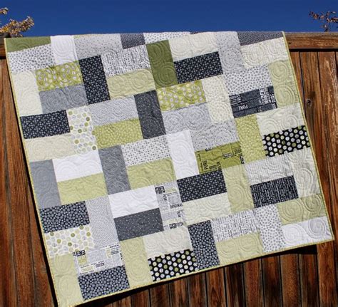 A Green And Gray Quilt Hanging On A Wooden Fence