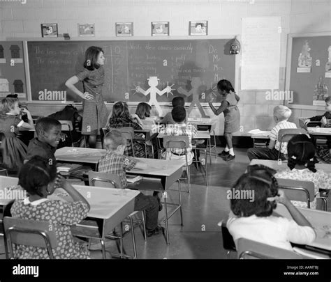 1960s Back View Of Grade School Classroom With Teacher At Front