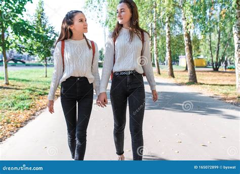 Two Teenage Girls Walk In Summer In Park Talk Walk After School And