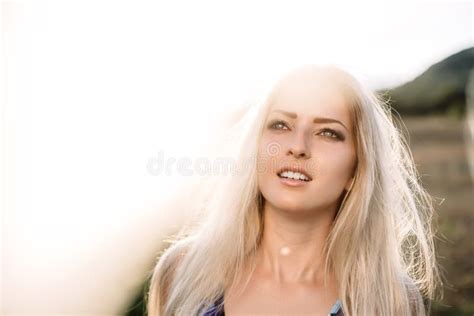Beautiful Dreamy Blonde Girl With Blue Eyes In A Light Turquoise Dress Lying On The Stones Stock
