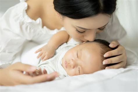 Giovane Madre Che Bacia Il Suo Neonato Nel Letto Genitore Ed Acceso Immagine Stock Immagine Di