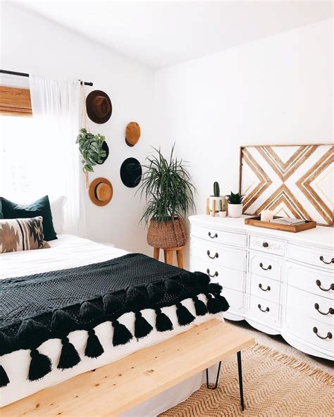 An elegant contemporary bedroom with a white upholstered bed, white nightstands, a chic chandelier and an artwork. How to Give a Black-and-White Bedroom the Boho Treatment ...