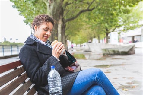 Premium Photo Young Woman Seated On A Bench Having Lunch In London