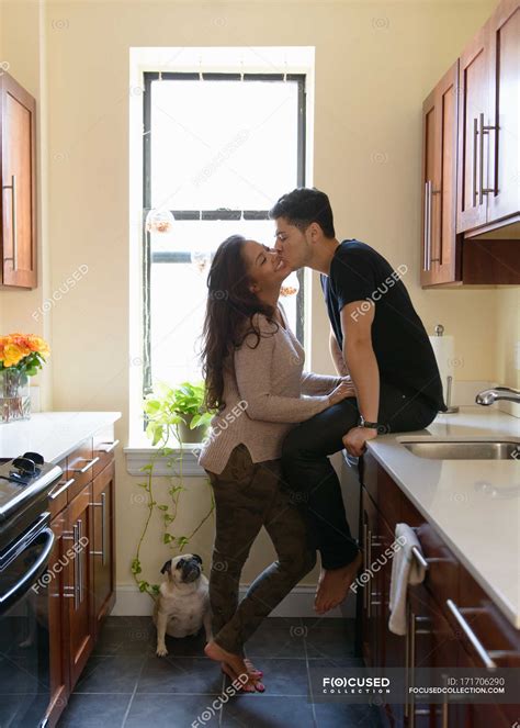 Young Couple Kissing In Kitchen — 20 To 24 Years Lifestyle Stock