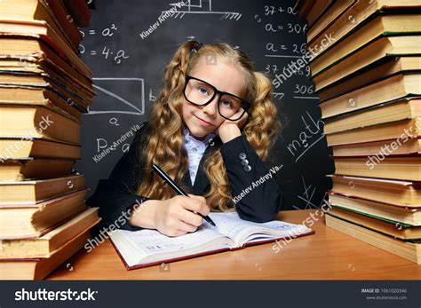 Portrait Of A Smart Schoolgirl In Glasses Posing With Books Over School