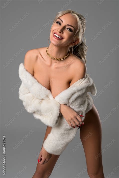 Sexy blonde woman undress white fur coat and look at camera 素材庫相片
