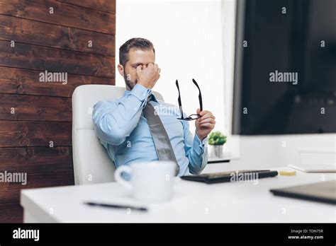 Tired Businessman From Heavy Workload Sitting At The Desk Stock Photo