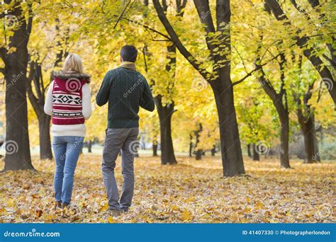 Rear View Of Young Couple Walking In Park During Autumn Stock Photo