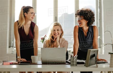 Smiling Young Women At Work Desk At Office Group Of Three Diverse