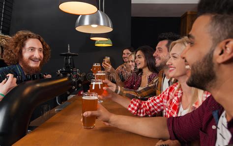 Young People Group In Bar Barman Friends Sitting At Wooden Counter Pub Drink Beer Stock Image
