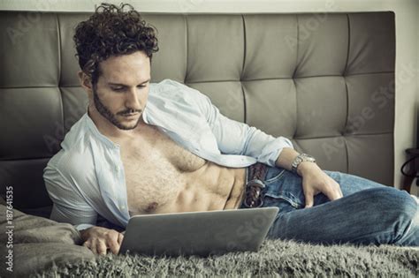 Sexy Handsome Man Laying With Open Shirt On His Bed With Laptop