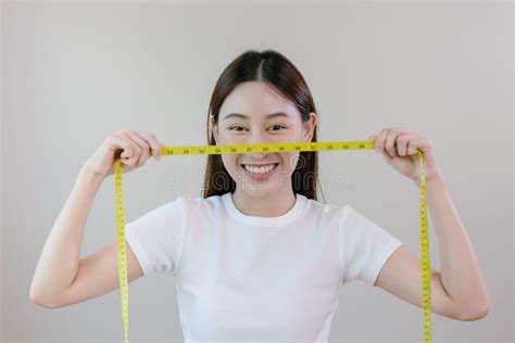 Asian Woman Holding A Tape Measure Yellow Around Her Waist Female