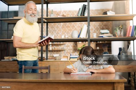Joyful Grandfather Dictating Words To His Granddaughter Stock Photo