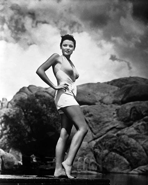 A Woman In A Bathing Suit Standing On The Edge Of A Body Of Water With