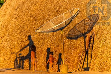 Sombras dos índios Kalapalos e da antena parabólica na Aldeia Aiha no