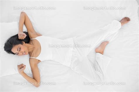 Lovely Peaceful Woman Stretching Out Lying On Her Bed In Bright Bedroom