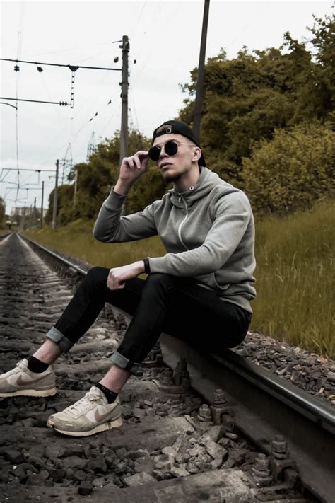 Man In Gray Jacket And Black Pants Sitting On Train Rail Photo Free