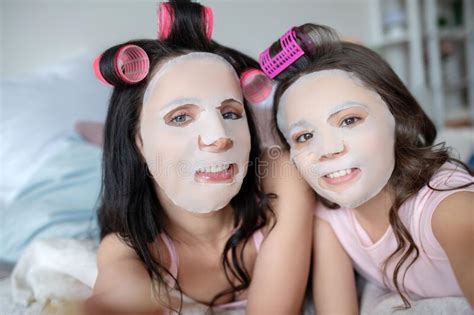 Mom And Daughter Feeling Amused With Facial Mask On Their Faces Stock