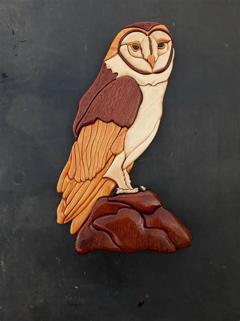 An Owl Sitting On Top Of A Piece Of Wood Carved Into The Shape Of A Rock