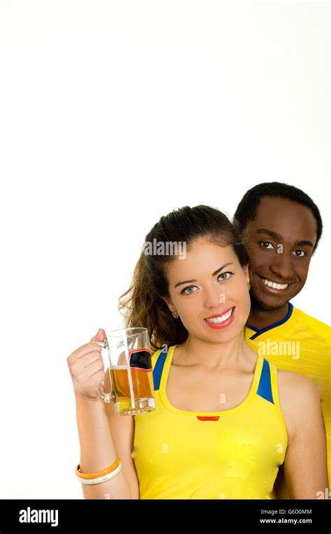 Charming Interracial Couple Wearing Yellow Football Shirts Posing For Camera Holding Beer Glass