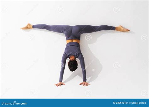 A Woman Practicing Yoga Performs The Adho Mukha Vrikshasana Exercise With Samakonasana Stands