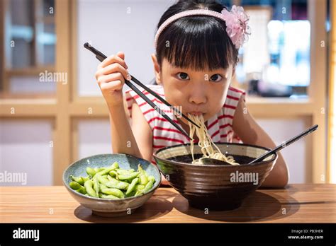 Asian Little Chinese Girl Eating Ramen Noodles At A Japanese Restaurant