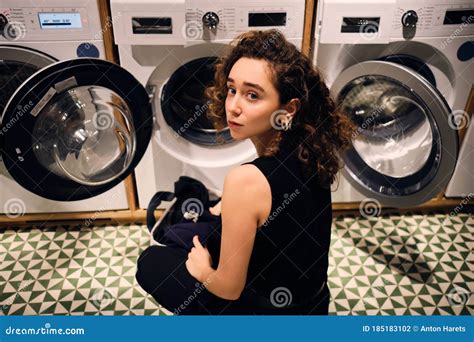 Attractive Brunette Girl Washing Clothes In Self Service Laundry Stock