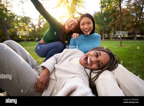 Three Multiracial Girls Lying On The Grass Taking Selfie Looking At
