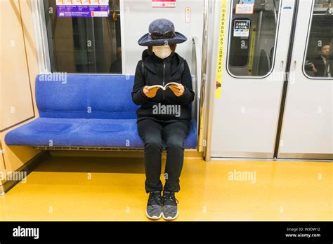 japan honshu tokyo subway subway female passenger wearing allergy mask and reading book