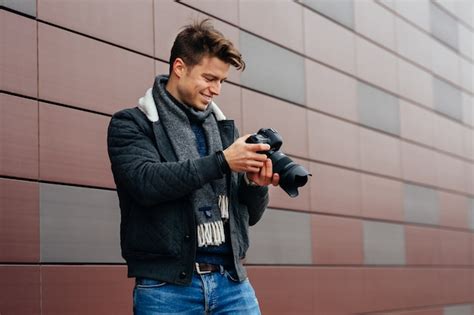 Free Photo Handsome Young Photographer Standing With Camera Outdoors