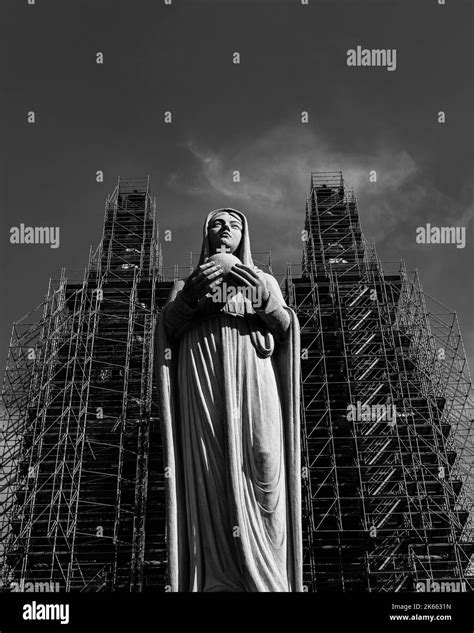 A Grayscale Low Angle Shot Of A Praying Virgin Mary Statue With A