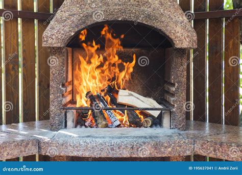 Stationary Barbecue Fireplace With Burning Wood At Summer Day Outdoor
