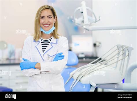 Smiling Female Dentist With Arms Crossed Standing At Medical Clinic