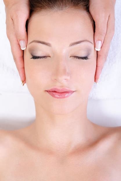 mulher jovem recebendo massagem facial em salão de spa foto grátis