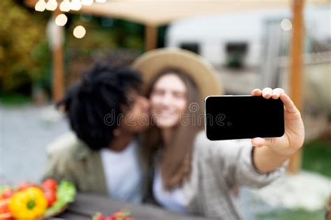 Loving Multiracial Couple Kissing And Taking Selfie Near Rv On Camping Trip In Autumn Mockup