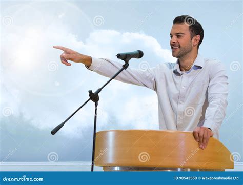 Businessman On Podium Speaking At Conference With Clouds Stock Photo