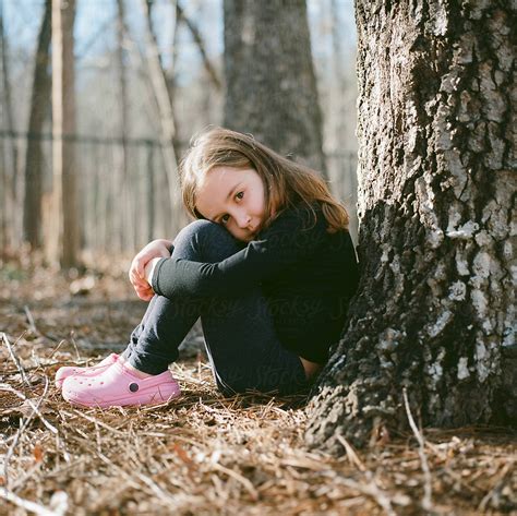 Beautiful Young Girl Sitting On The Ground With The Back To A Tree By