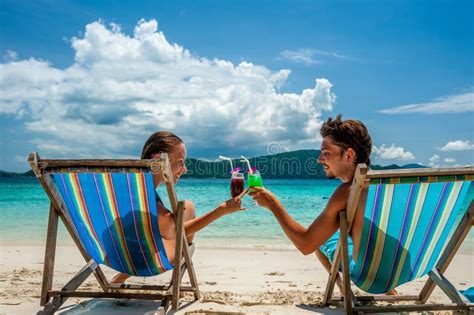 Couple In Loungers Clinking Their Glasses On A Tropical Beach Stock Image Image Of Holiday