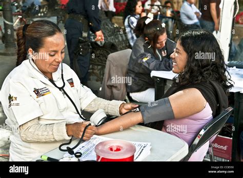 Pretty Young Mexican Woman Smiles As Nurse Takes Her Blood Pressure In