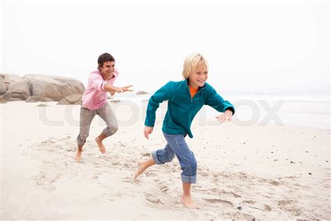 Father Chasing Son Along Winter Beach Stock Image Colourbox