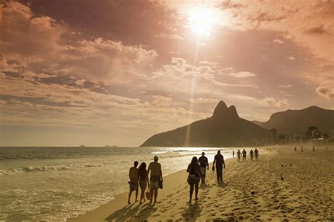 People Walking On The Beach At Sunset By Buena Vista Images
