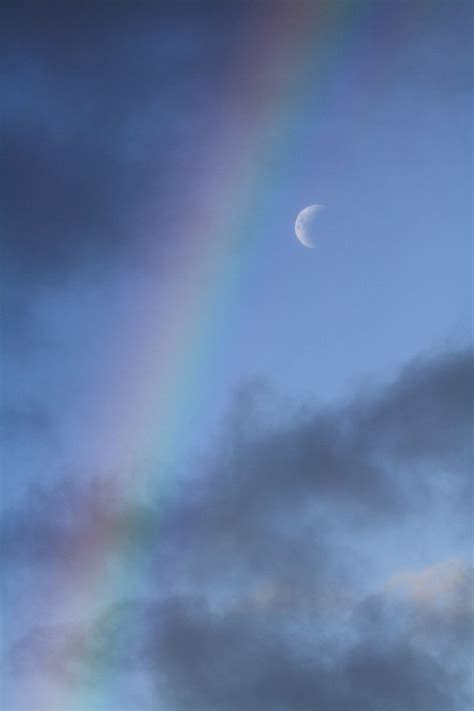 A Rainbow In The Sky With Clouds And A Half Moon
