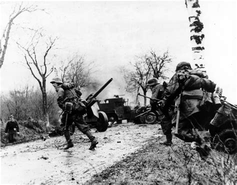 German Troops Advancing Past Abandoned American Equipment During The