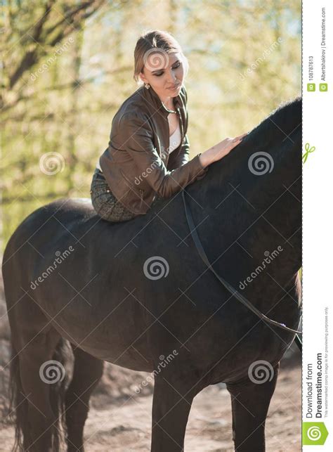 Brunette Woman Riding Dark Horse At Summer Green Forest Stock Image