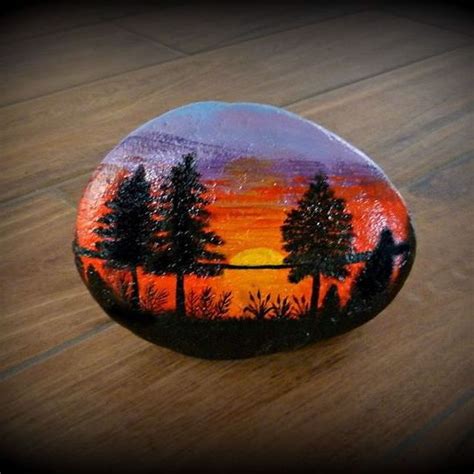 A Painted Rock Sitting On Top Of A Wooden Floor Next To A Tree Filled