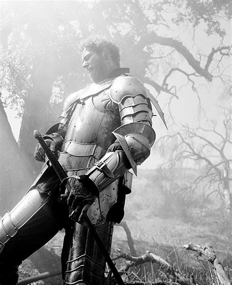 A Man Dressed In Armor Standing Next To A Tree