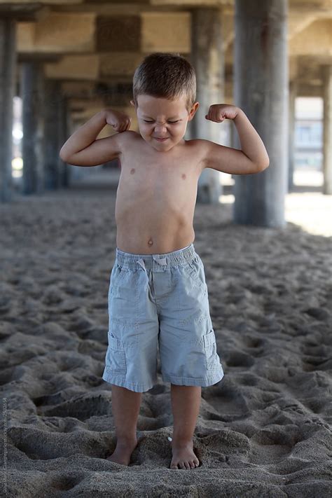 Little Boy Flexing His Muscles On The Beach By Stocksy Contributor
