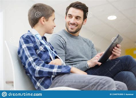 Padre Con Hijo En La Sala De Espera Del Hospital Mirando El Tablet Foto