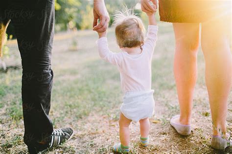 Parents Walking With Their Little Baby Boy Holding Hands By Stocksy